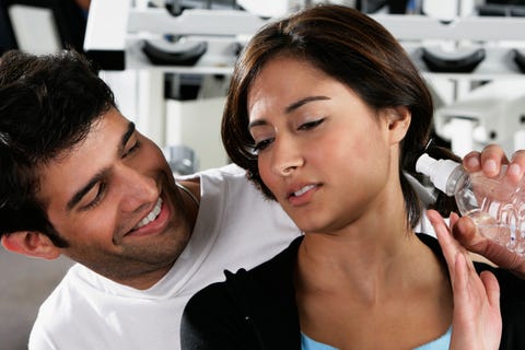 close up of a young man offering a bottle to a young woman in a gym