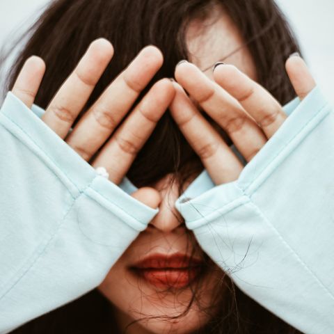 closeup of a young woman covering eyes