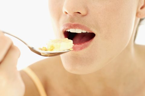 close up of a young woman eating a spoon of cereal
