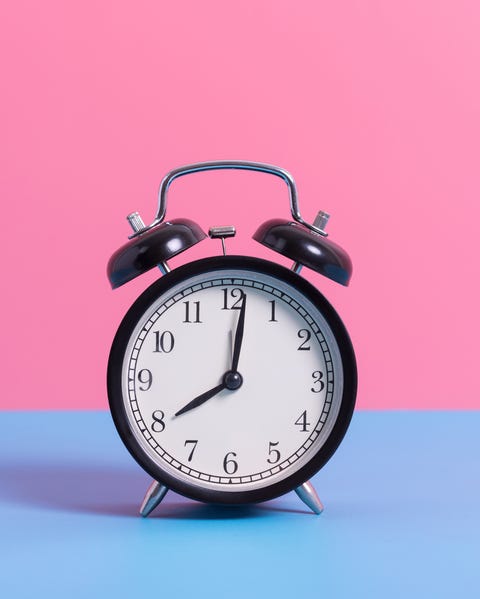 Close-Up Of Alarm Clock On Blue Table Against Pink Wall