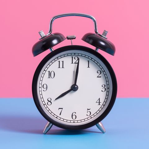 close up of alarm clock on blue table against pink wall