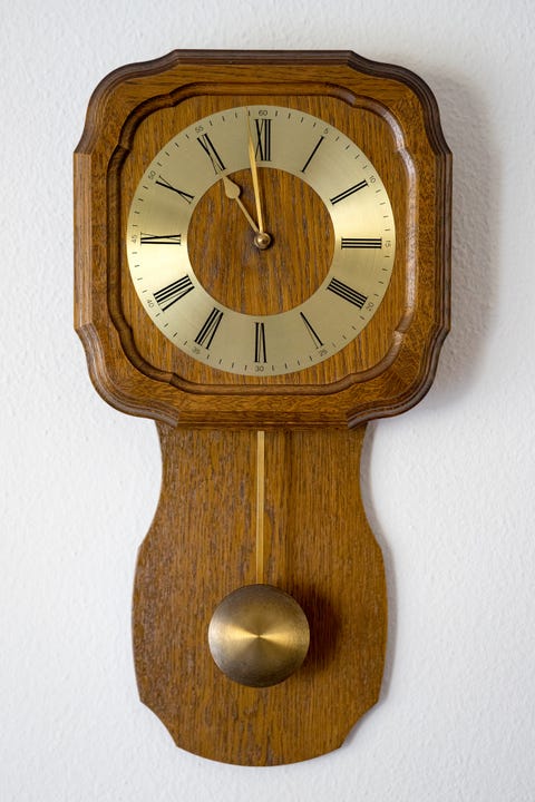 Close-Up Of Antique Wall Clock Against White Wall