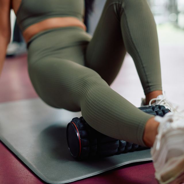 close up of athletic woman using foam roller while exercising in a gym