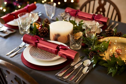 Close up of Christmas table setting with Christmas crackers arranged on plates and red and green table decorations, elevated view