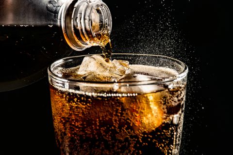 close up of drink pouring in drinking glass against black background