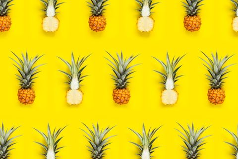 Close-Up Of Halved Pineapples Arranged On Yellow Background