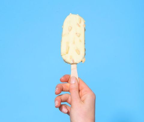 Close-Up Of Hand Holding Ice Cream Against Blue Background