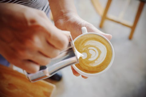 Close-Up Of Hand Pouring Milk In Coffee close up of hand pouring milk in coffee