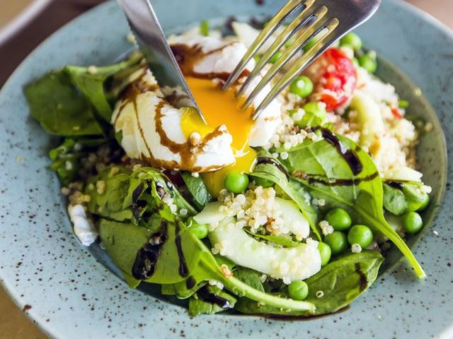 Close up of healthy salad with quinoa, green peas, spinach and poached egg