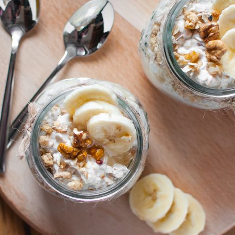 close up of homemade banana oats in a glass jar on wooden background, top view