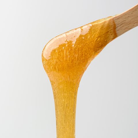 close up of honey dipper against white background