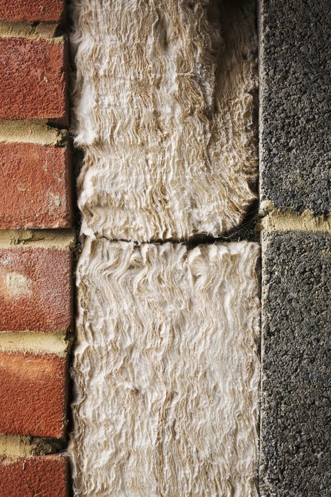 Close up of insulation between a brick and cinder block wall.