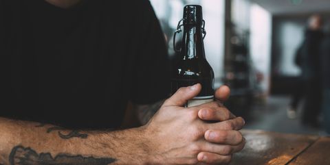 close up of man holding beer bottle