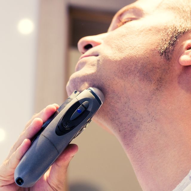 close up of man using hair clipper in bathroom