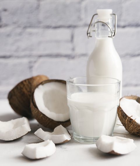 Close-up of milk with coconuts on table against brick wall