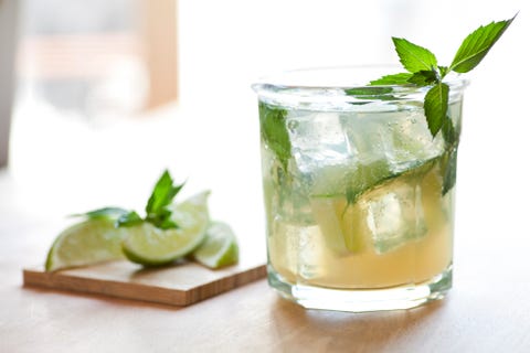 Close up of mojito glass with lemon slices blurred in back