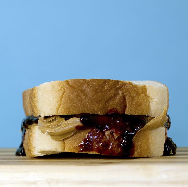 close up of peanut butter and jam in bread on table against blue background