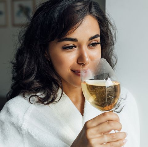 closeup of smiling woman drinking wine while standing at home