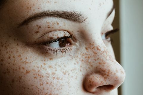 close up of thoughtful woman with freckles on face