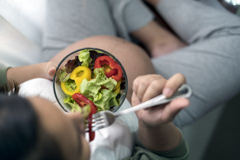 close up of  top view pregnant woman eating salad at home