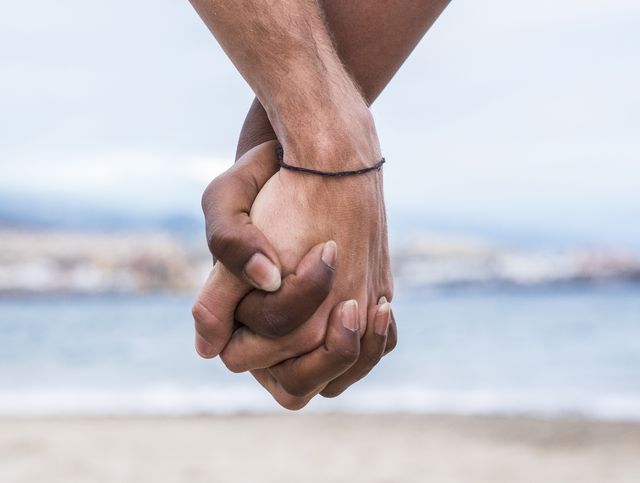close up of two hands connected on the beach