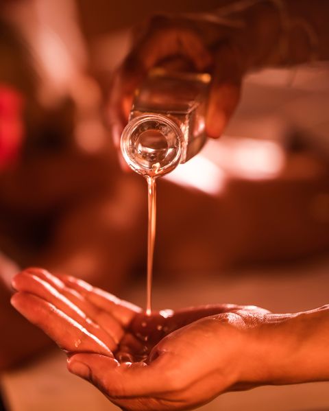 Close up of unrecognizable therapist pouring oil before massage treatment at the spa.
