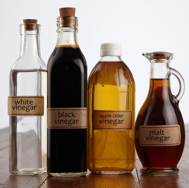Close-Up Of Various Vinegars On Table Against White Background