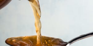 Close-Up Of Vinegar Pouring In Spoon Against White Background