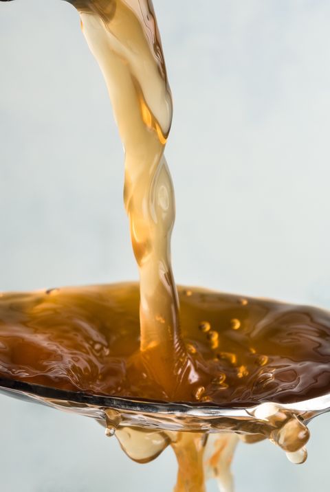 Close-Up Of Vinegar Pouring In Spoon Against White Background
