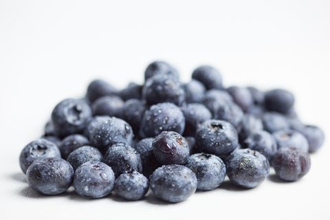 Close-Up Of Wet Blueberries Against White Background