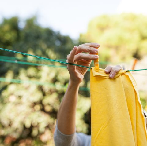 Close-up of woman hanging up yellow blanket on clothesline