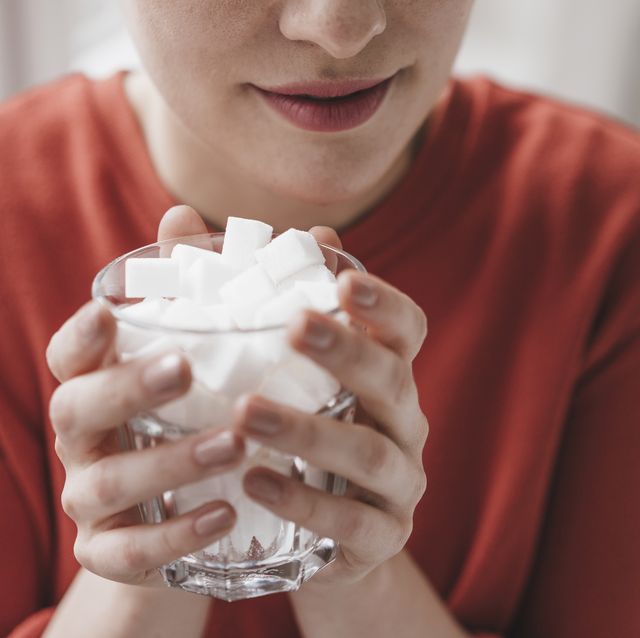 close up of woman holding glass full of sugar cubes