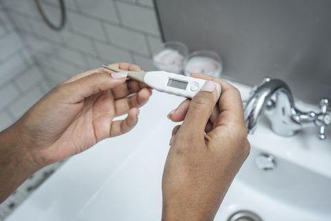 close up of woman holding thermometer in bathroom