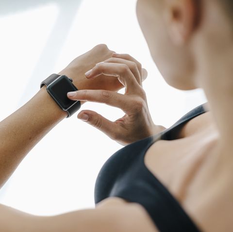 close up of woman in sportswear adjusting her smartwatch