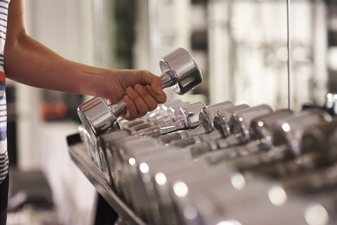 Close up of woman selecting dumbbell weight at gym.
