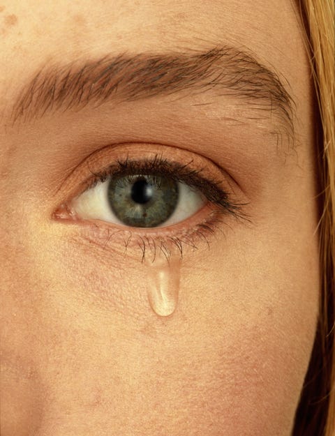 Close-up of woman's face with teardrop falling from eye