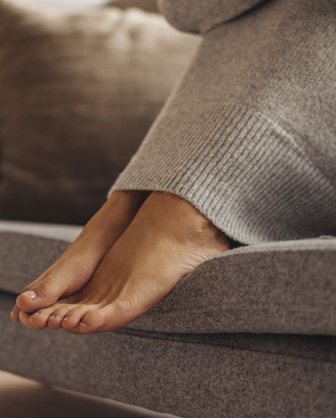 Close-up of woman's feet sitting on couch