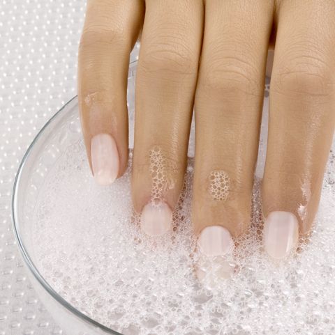 Close up of woman's hand in bowl of soapy water