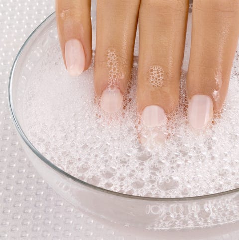 Close up of woman's hand in bowl of soapy water