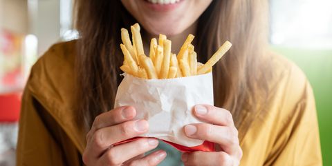 close up of young asian woman holding a french fries before eating