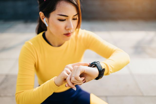 close up of young sports woman checking smartwatch while exercising outdoors in the city