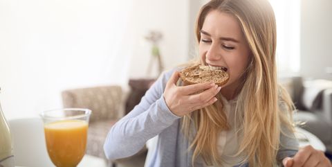 close up of young woman eating breakfast at home