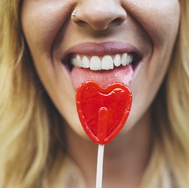 Close-up of young woman licking heart-shaped lollipop