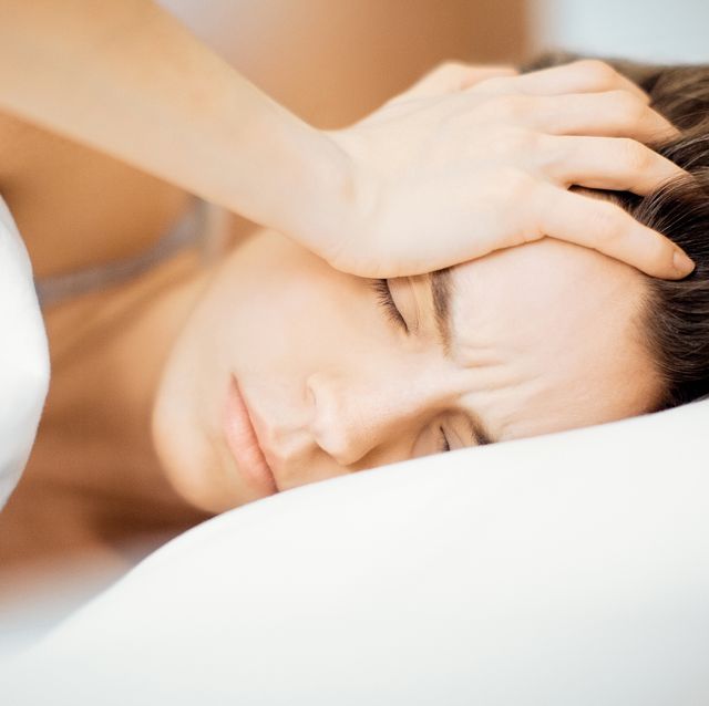 Close-Up Of Young Woman With Headache Lying On Bed