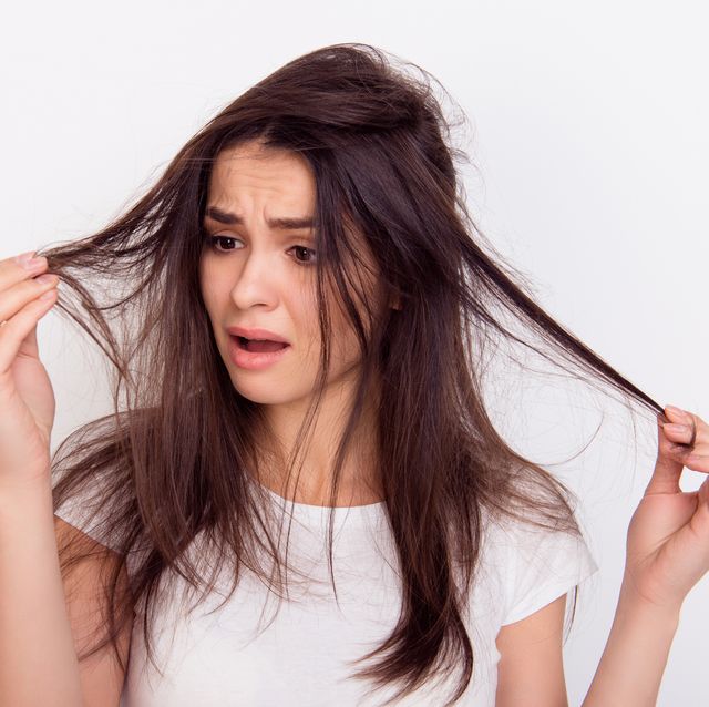 close up portrait of frustrated young brunette woman with messed hair on white background