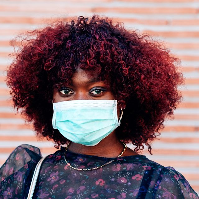 close up portrait of young black woman wearing face medical mask to prevent coronavirus infection