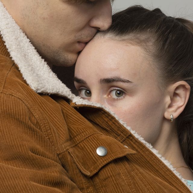 close up portrait worried young woman in arms of boyfriend