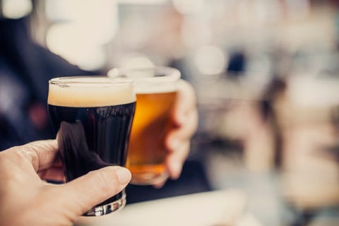 Close-up shot of a couple cheering with two different kind of beers, on the patio of a microbrewery Close-up shot of a couple cheering with two different kind of beers, on the patio of a microbrewery