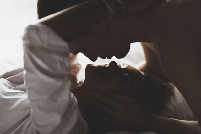 closeup silhouette of couple kissing with love and passion in bed