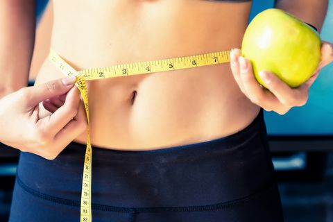 close up slim young woman measuring her waist with a tape measurehealthy lifestyle, diet nutrition concept